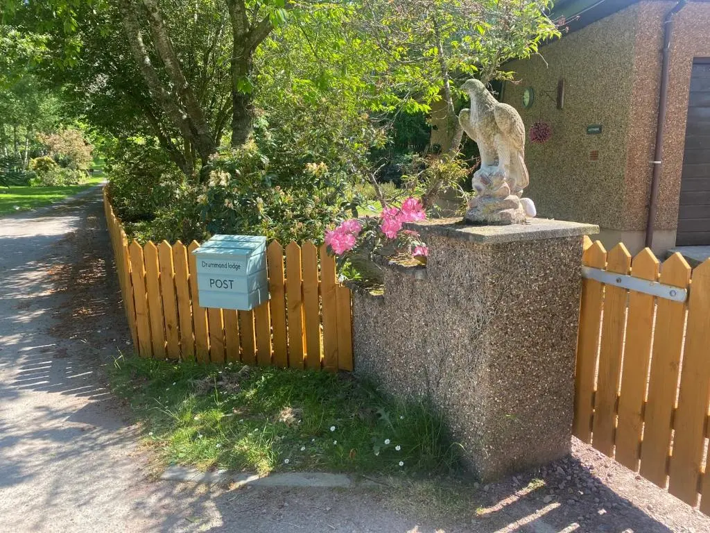 a statue of a bird on a fence with flowers at Drummond House - Pets welcome free, 3 acres of gardens, free parking in Brackley