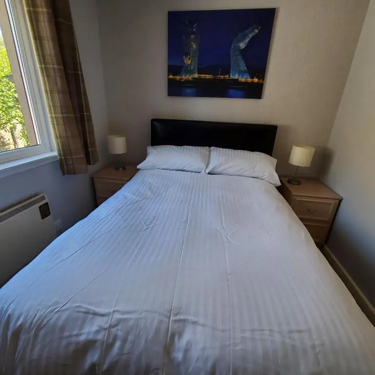 a large white bed in a bedroom with two night stands at Aviemore Bungalow, Dalfaber in Aviemore