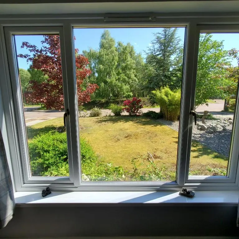 a window with a view of a yard at Aviemore Bungalow, Dalfaber in Aviemore
