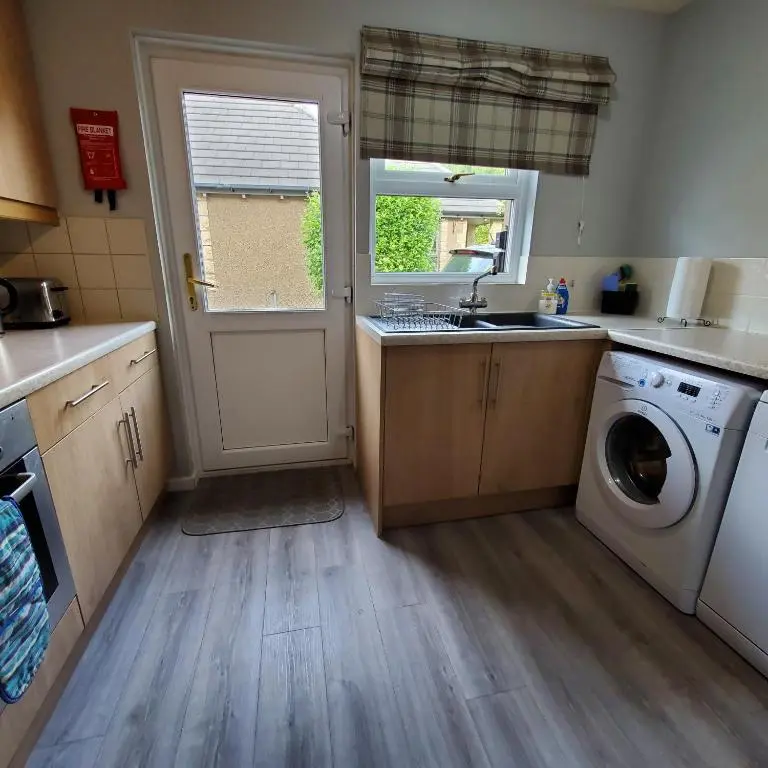 a kitchen with a sink and a washing machine at Aviemore Bungalow, Dalfaber in Aviemore