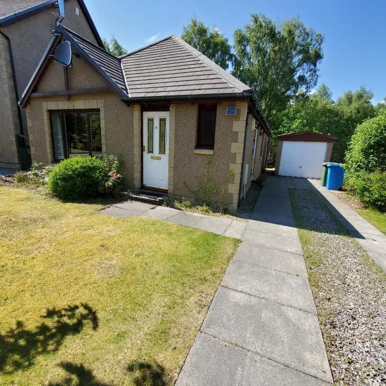 a house with a sidewalk in front of it at Aviemore Bungalow, Dalfaber in Aviemore
