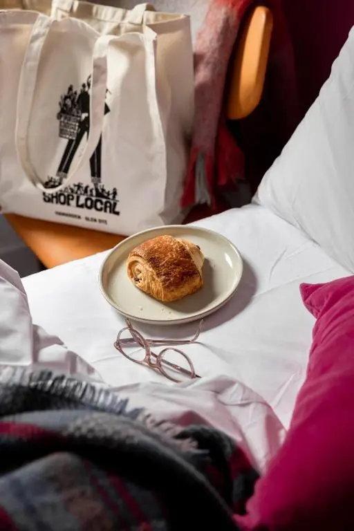 a plate of food on a bed with a bag at Number 5 Steading Cottage in Banchory