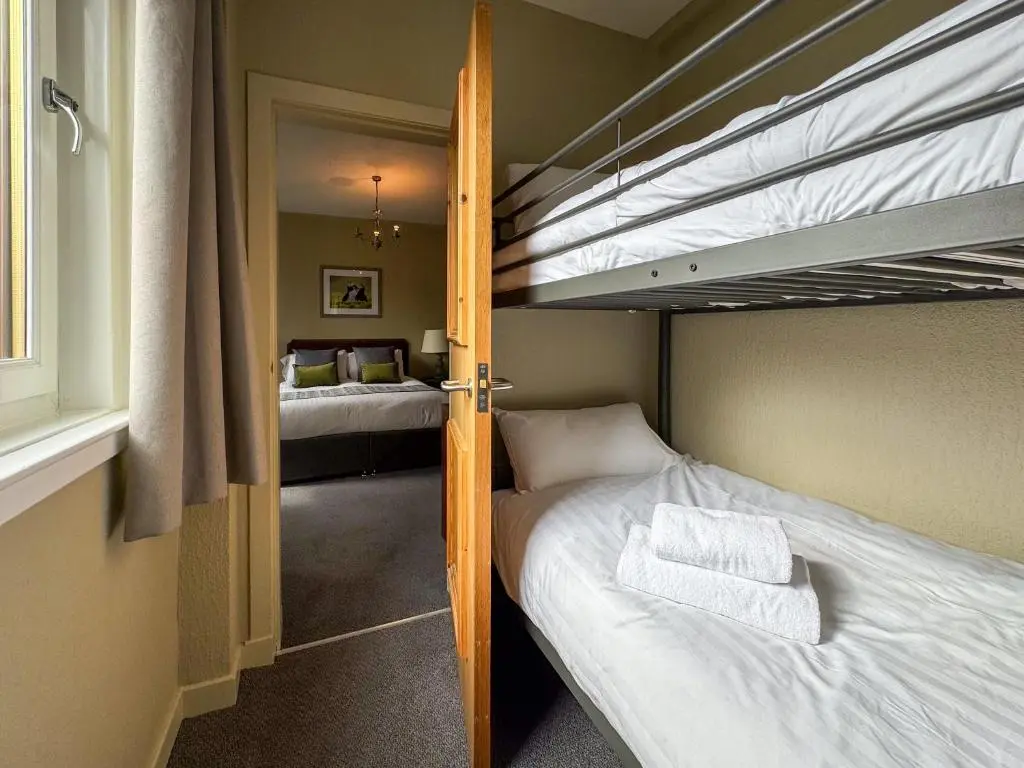 a bedroom with two bunk beds and a hallway at The Royal Hotel in Ullapool