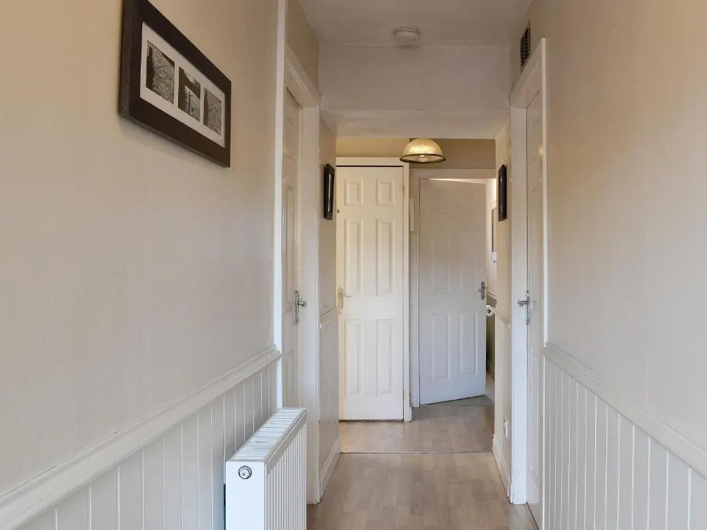 a hallway with white walls and a white door at Honey Cottage in Auchnarrow