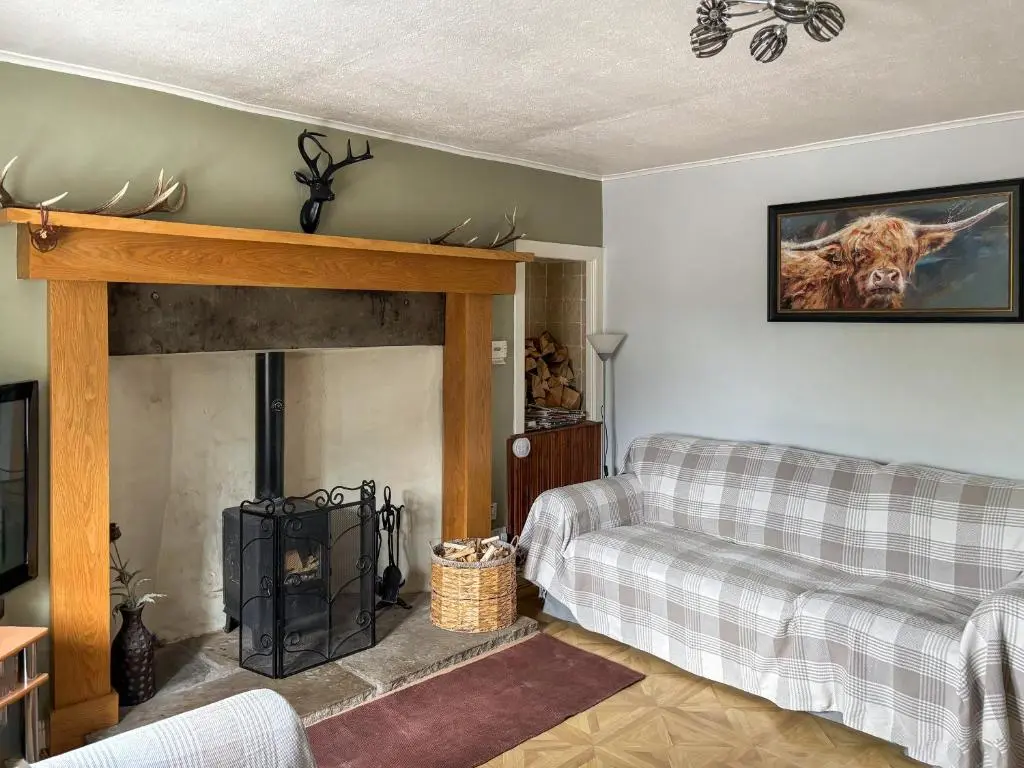 a living room with a couch and a fireplace at Honey Cottage in Auchnarrow