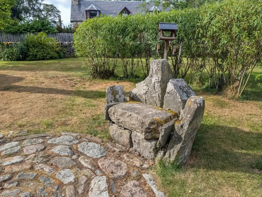 a stone bench sitting in the middle of a yard at Rowan Cottage in Carrbridge