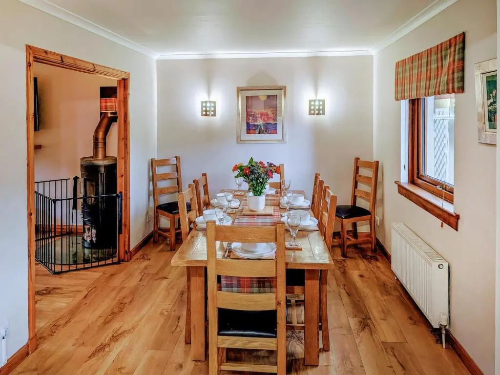 a dining room with a wooden table and chairs at Rowan Cottage in Carrbridge