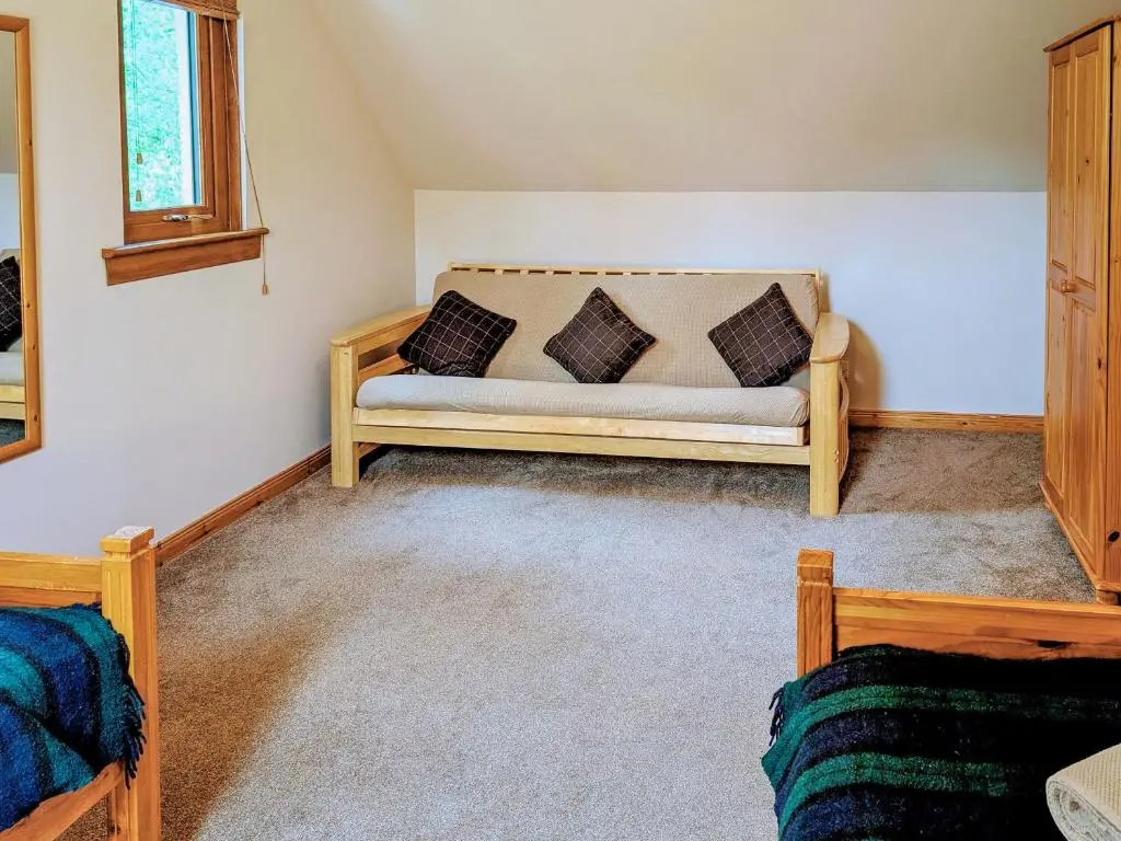 a couch in the corner of a room at Rowan Cottage in Carrbridge