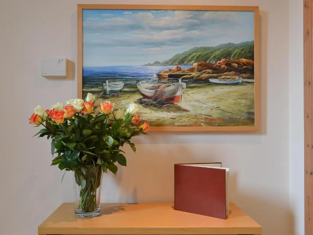 a vase of flowers on a table with a painting at 3 Allt Mor in Aviemore