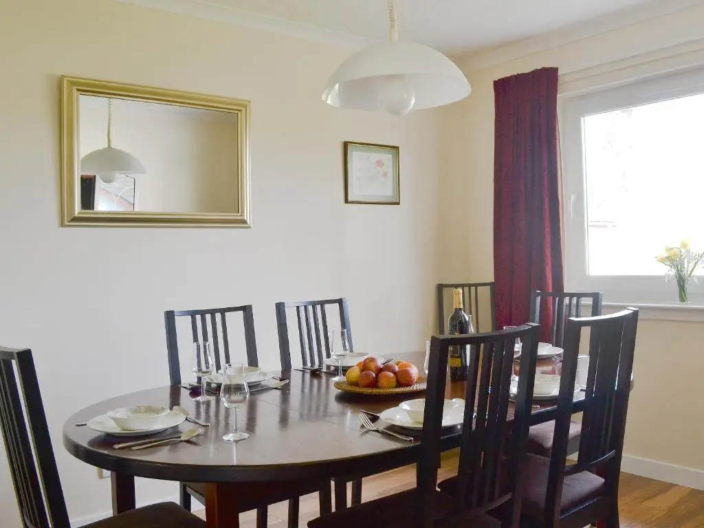 a dining room table with a bowl of fruit on it at Tall Pines in Carrbridge