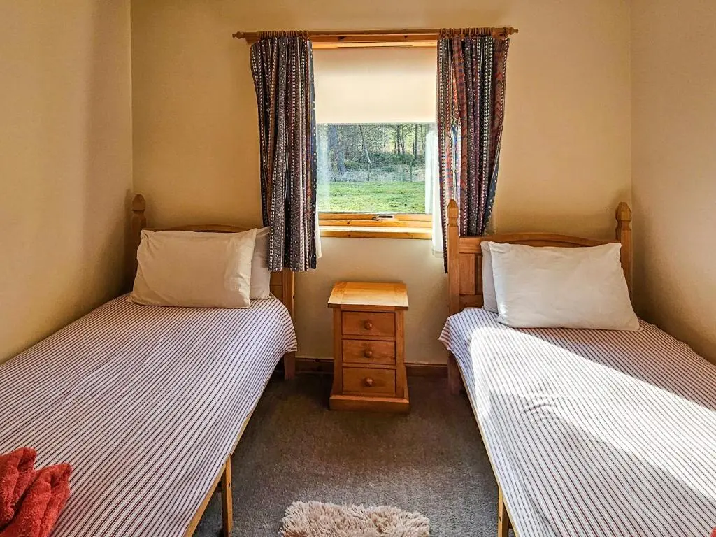 two beds in a small room with a window at Cotterton Beag in Nethy Bridge