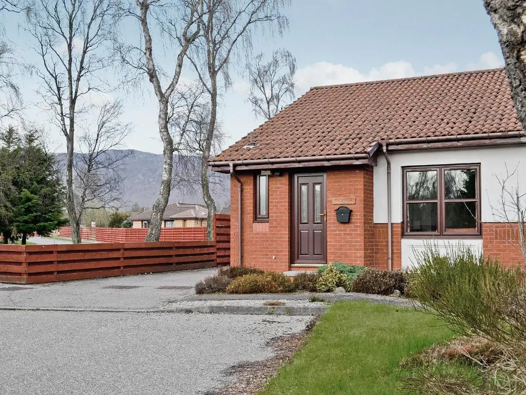 a brick house with a fence in front of it at Glenrothay in Aviemore
