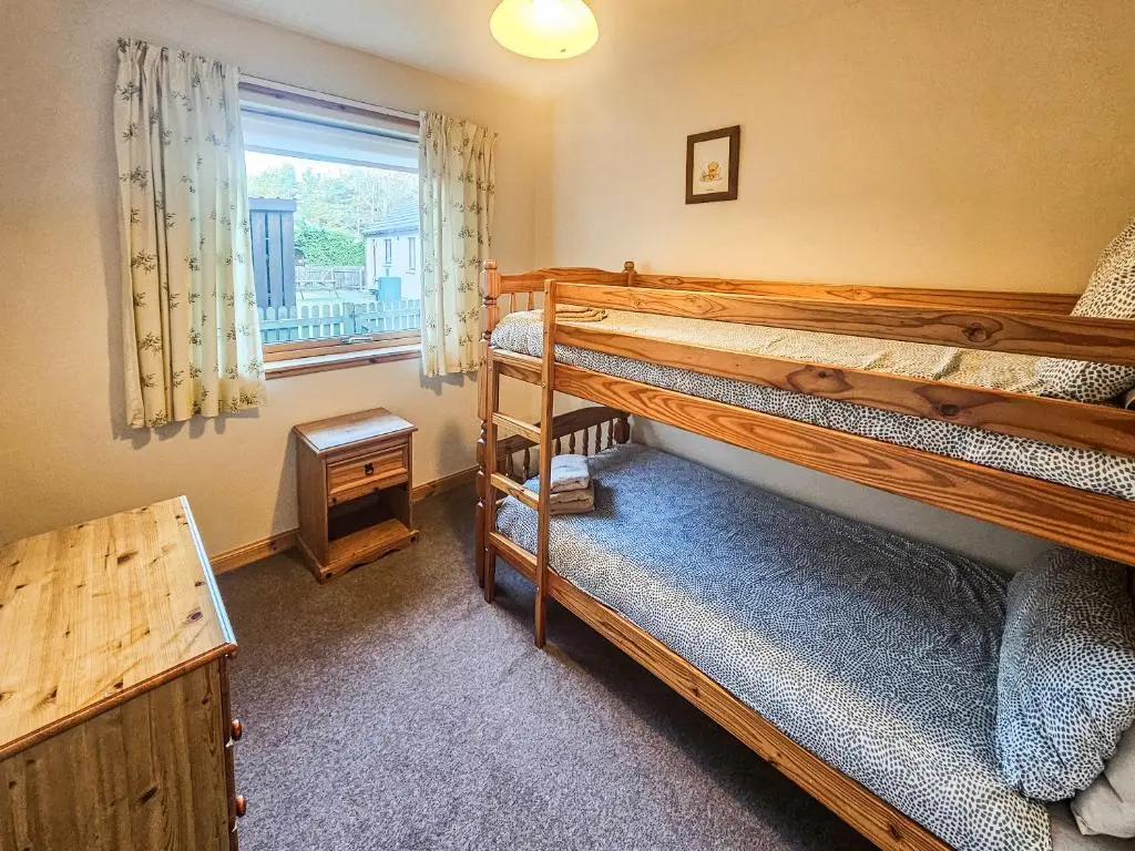a bedroom with two bunk beds and a window at Clunymhore in Nethy Bridge