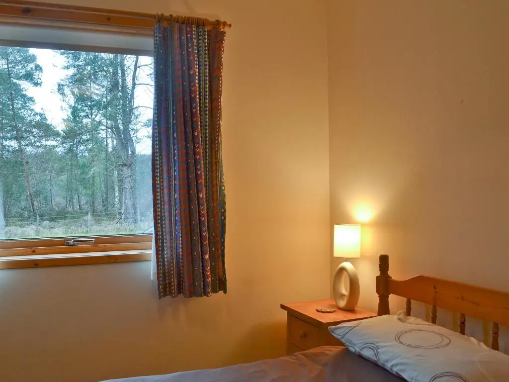 a bedroom with a bed and a window at Clunymhore in Nethy Bridge