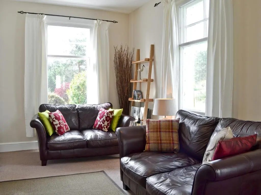 a living room with a leather couch and two chairs at Caberfeidh in Skye of Curr