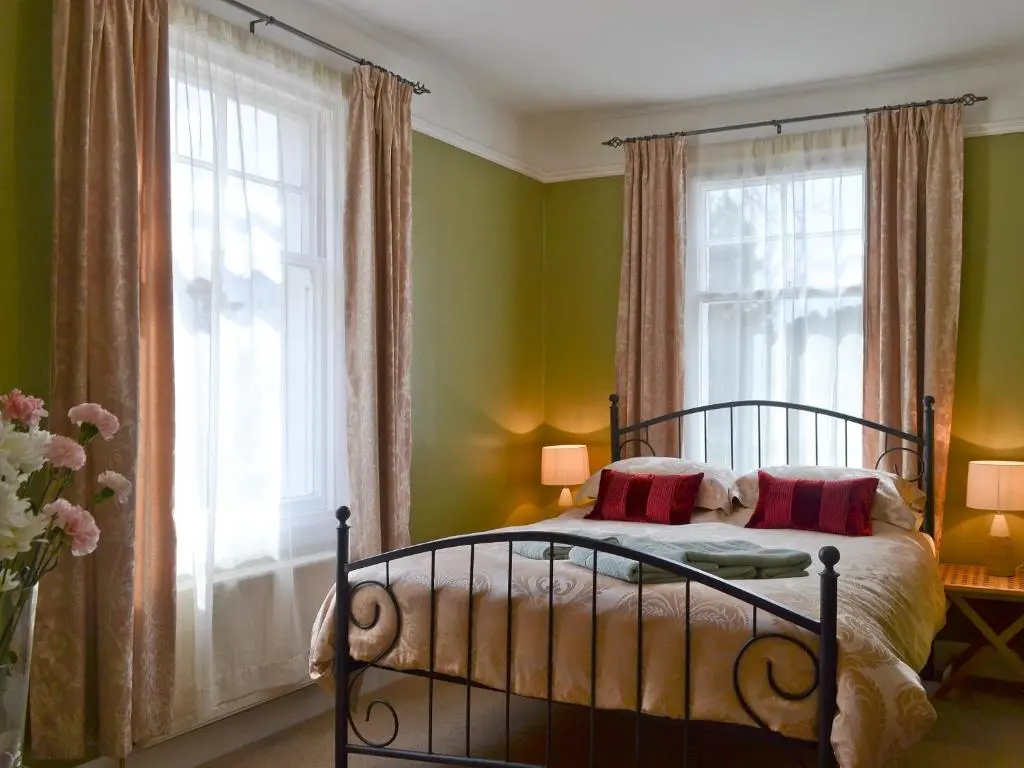 a bedroom with green walls and a bed with red pillows at Caberfeidh in Skye of Curr