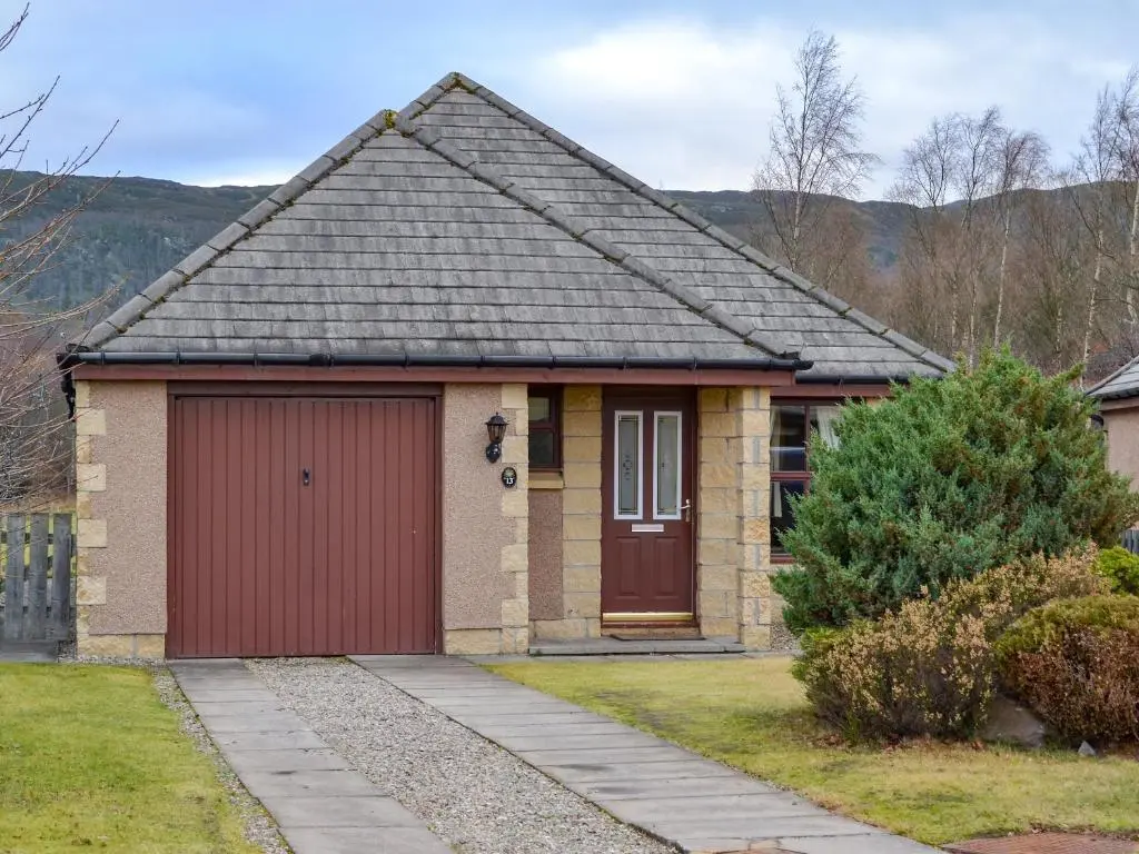 a small brick house with a red garage at Birch Tree Cottage in Aviemore