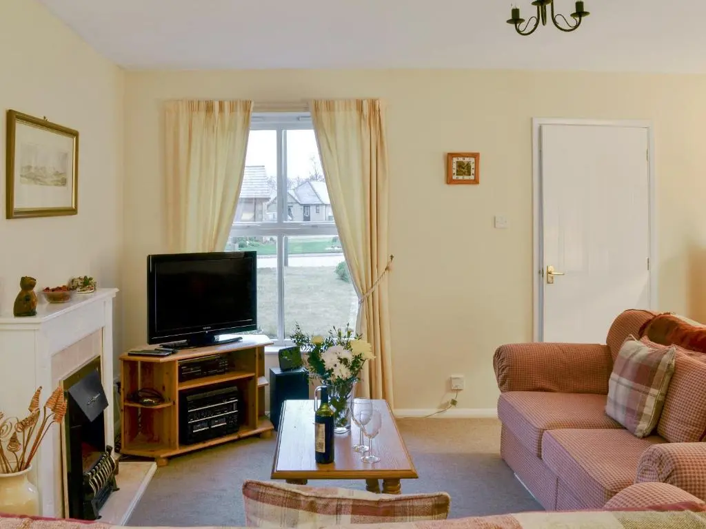 a living room with a couch and a tv at Birch Tree Cottage in Aviemore