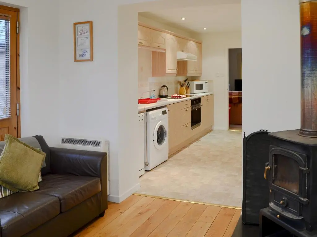 a living room with a couch and a kitchen at Birch Tree Cottage in Aviemore