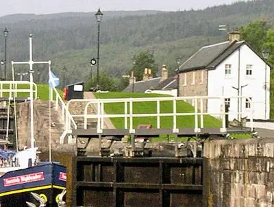 a boat is docked in a harbor with a house at Lockside Lower Flat in Fort Augustus