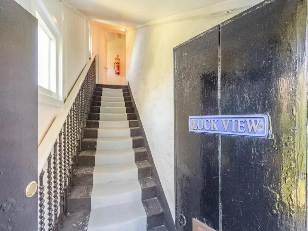 a staircase with a blue sign on the wall at Lockview Upper Flat in Fort Augustus