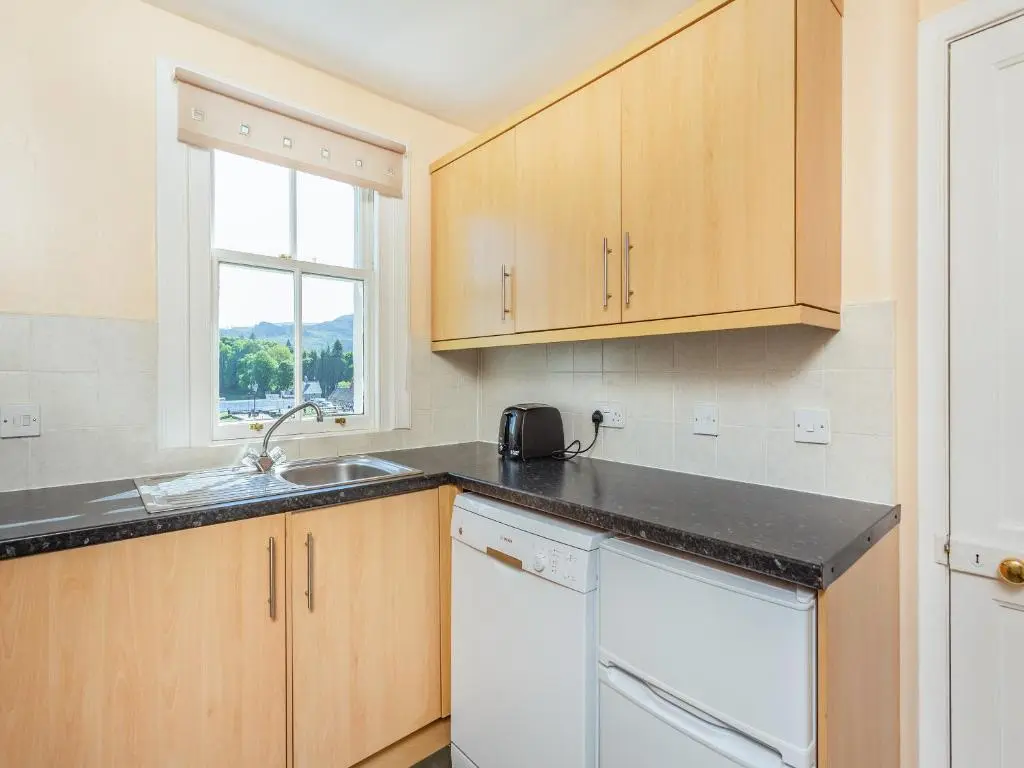 a kitchen with wooden cabinets and a sink and a window at Lockview Upper Flat in Fort Augustus