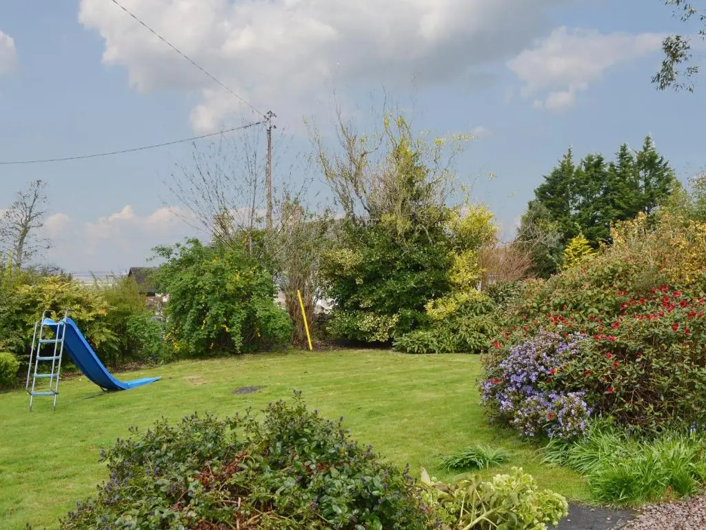 a yard with a playground with a blue slide at Culcharry Cottage in Cawdor