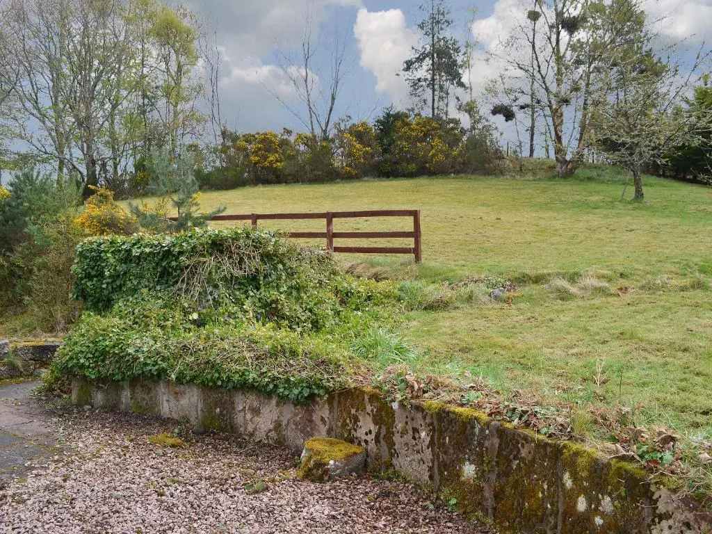 a park with a fence and a field with grass at Culcharry Cottage in Cawdor