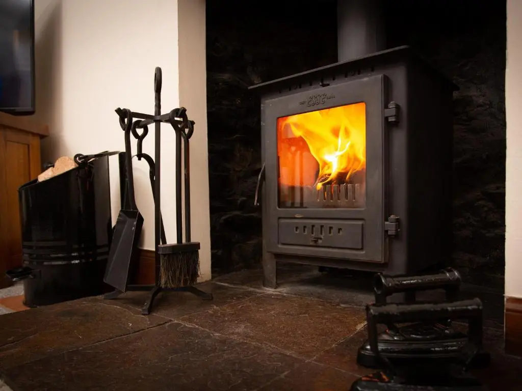 a stove with a fire in it in a room at Craigellachie Cottage in Croy