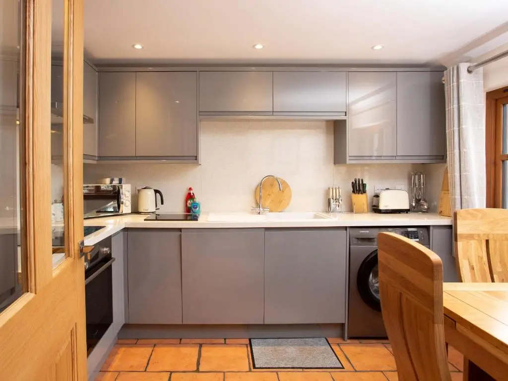 a kitchen with stainless steel appliances and a table at Craigellachie Cottage in Croy