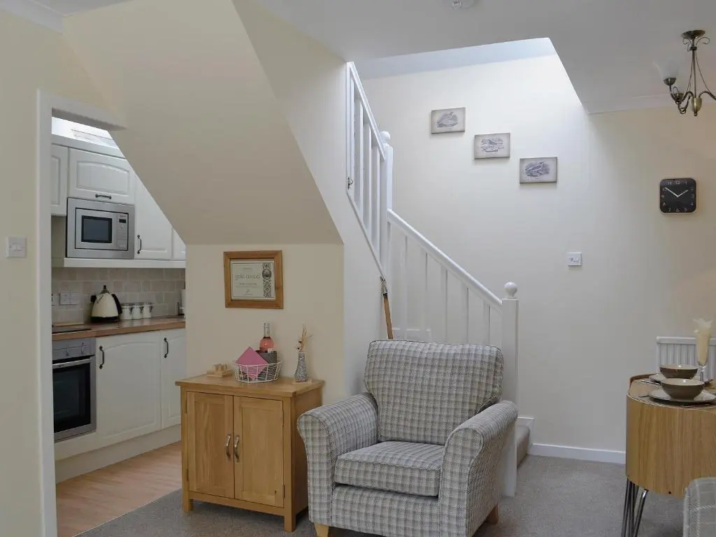 a living room with a chair and a staircase at Song Bird Cottage in Lochend
