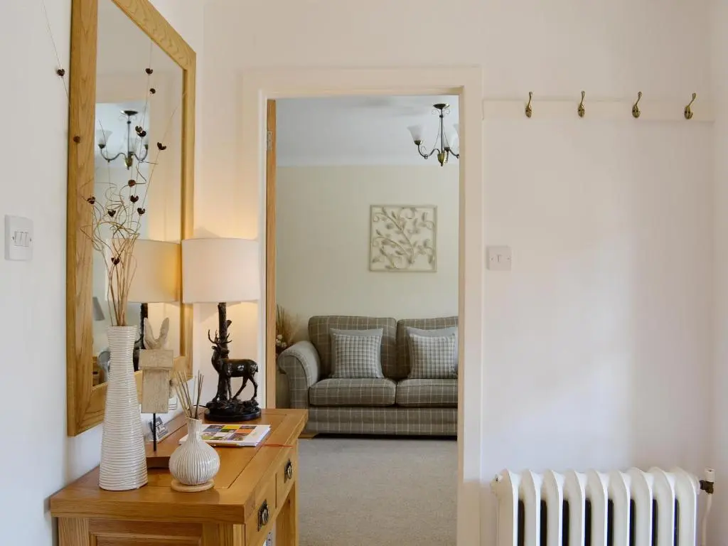 a living room with a couch and a table with a mirror at Song Bird Cottage in Lochend