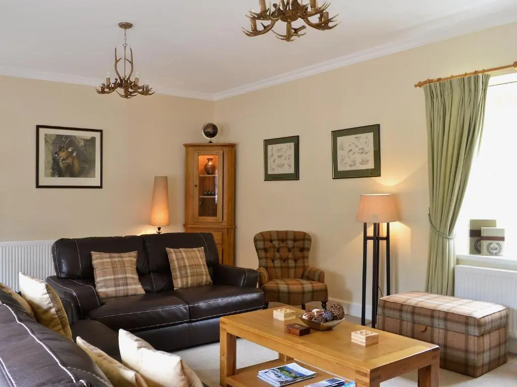 a living room with a couch and a table at Ladybird Cottage in Lochend