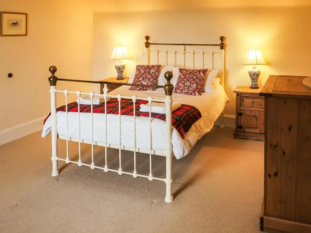 a bedroom with a white bed and a wooden dresser at Einich in Newtonmore