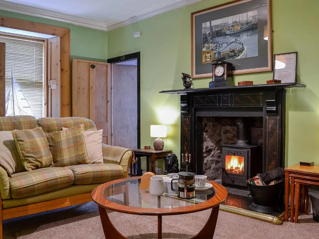 a living room with a couch and a fireplace at Boatmans Cottage - 27787 in Portessie