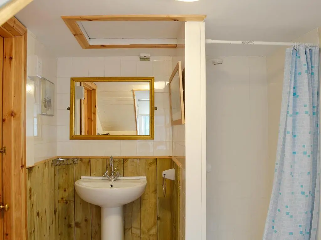 a bathroom with a sink and a mirror at Boatmans Cottage - 27787 in Portessie