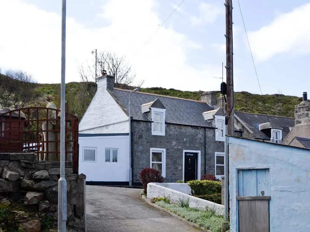 a house with a white garage in a street at Boatmans Cottage - 27787 in Portessie