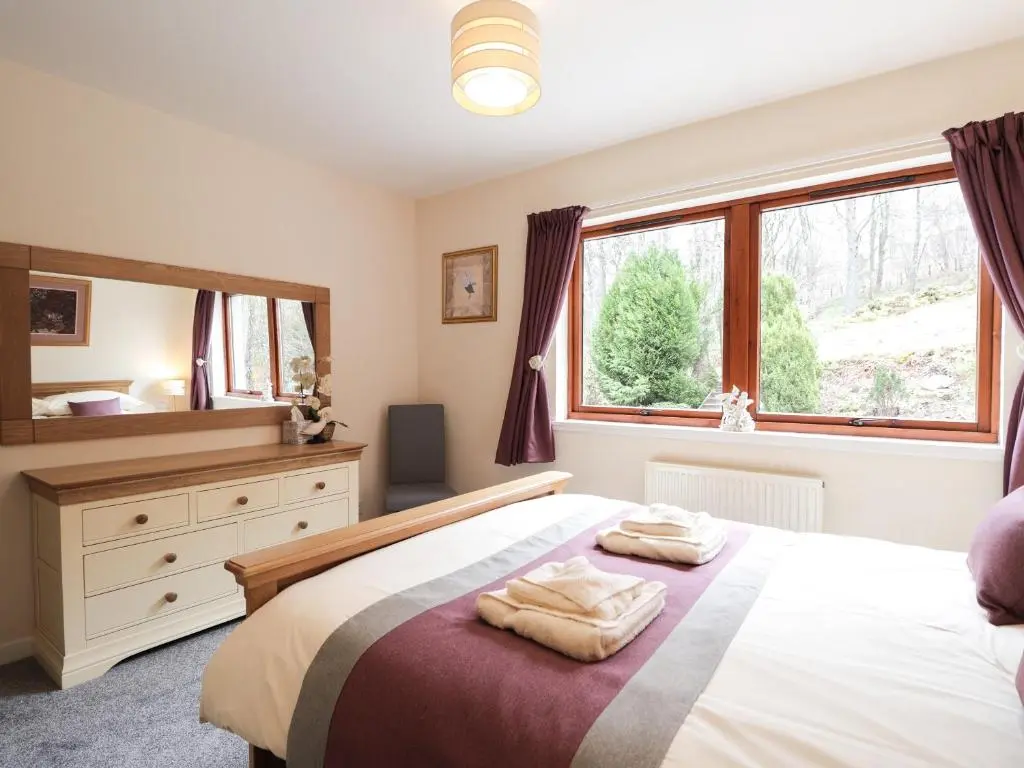 a bedroom with a bed with two towels on it at Holly Cottage in Gorstan