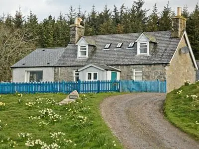 a house with a blue fence next to a dirt road at Reid's Cottage in Lairg