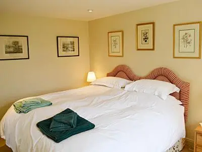 a bedroom with a white bed with a green bow on it at Reid's Cottage in Lairg
