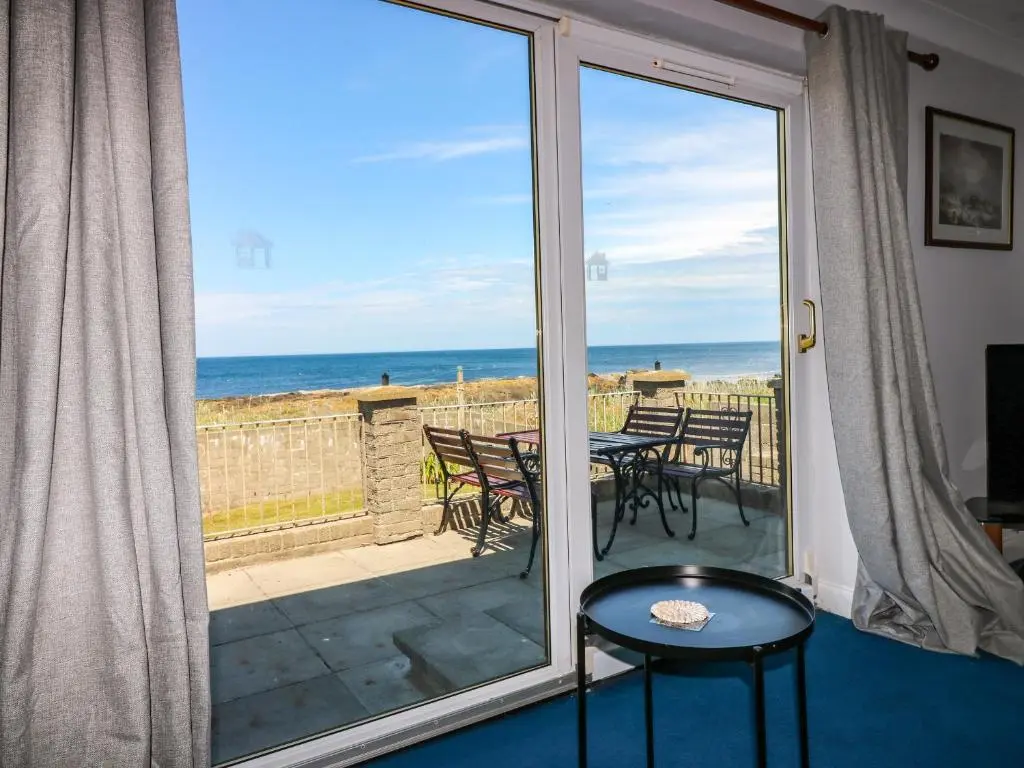 a view of the ocean from a room with a sliding glass door at Shoreline House in Fraserburgh