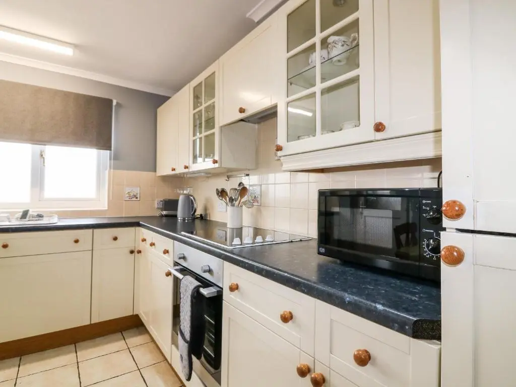 a kitchen with white cabinets and a black counter top at Shoreline House in Fraserburgh
