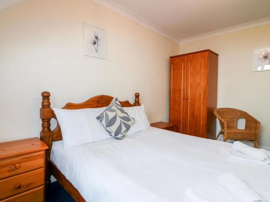 a bedroom with a bed and a wooden dresser at Shoreline House in Fraserburgh