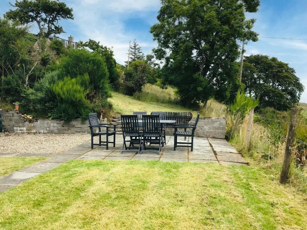 a patio with chairs and a table in the grass at Owl Cottage in Kilmote