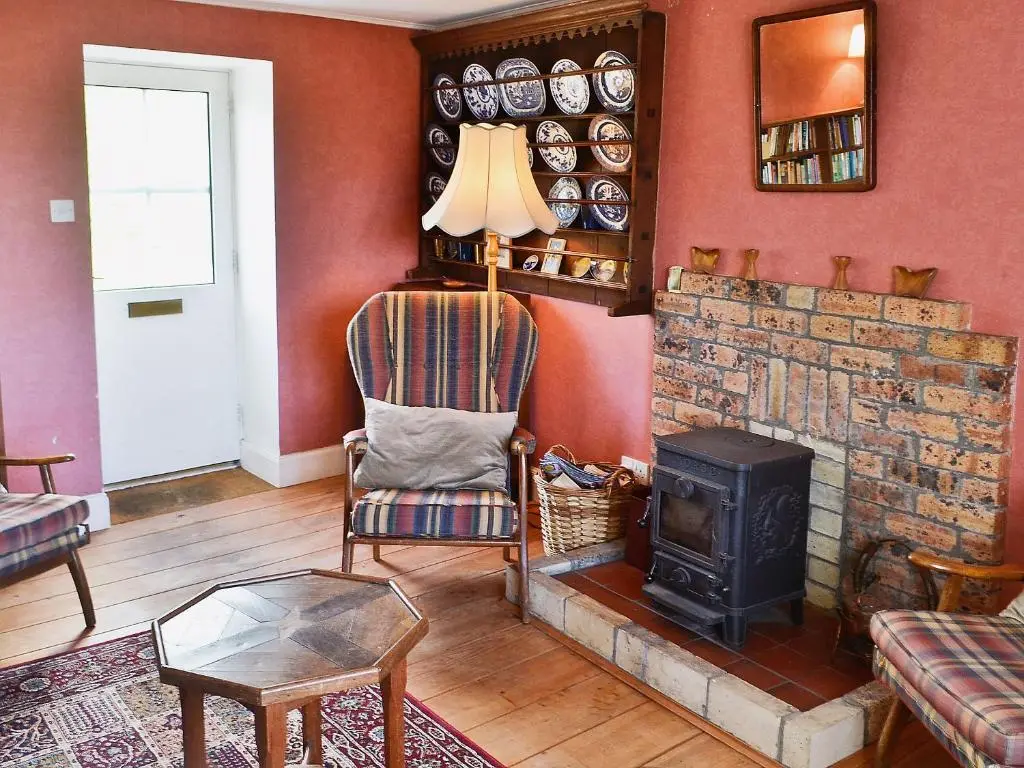 a living room with a brick fireplace and a chair and a stove at Rosscot in Ankerville