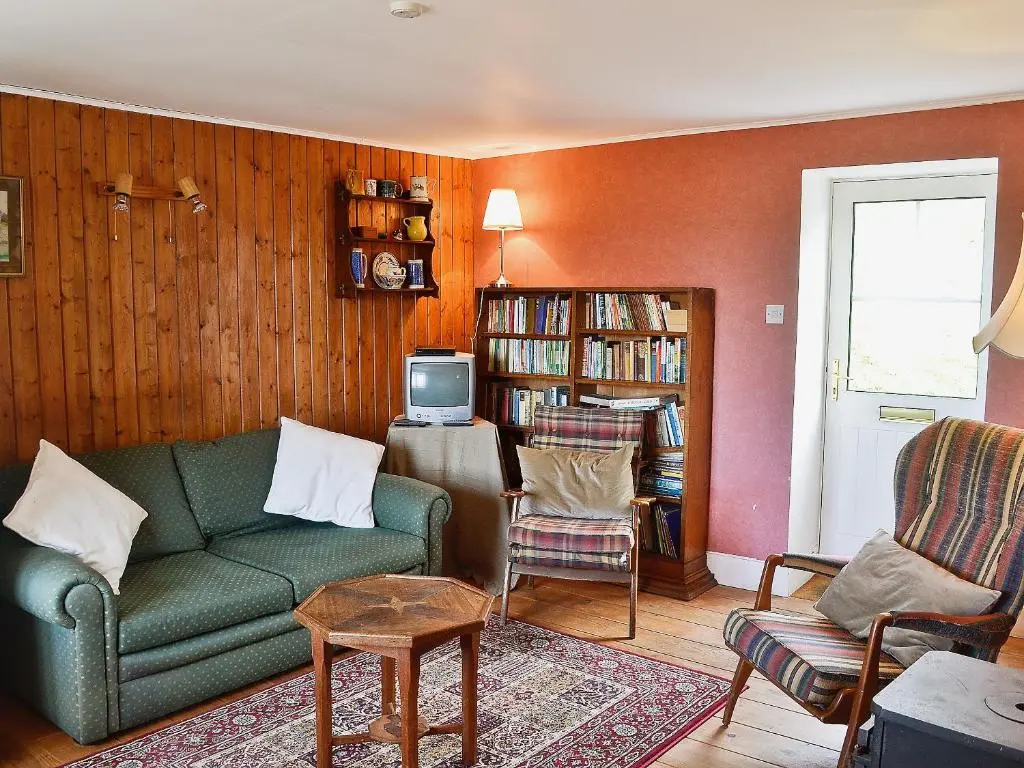 a living room with a green couch and a tv at Rosscot in Ankerville