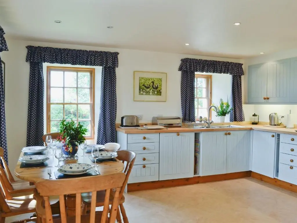 a kitchen with a table and a dining room at The Cottage in Ankerville