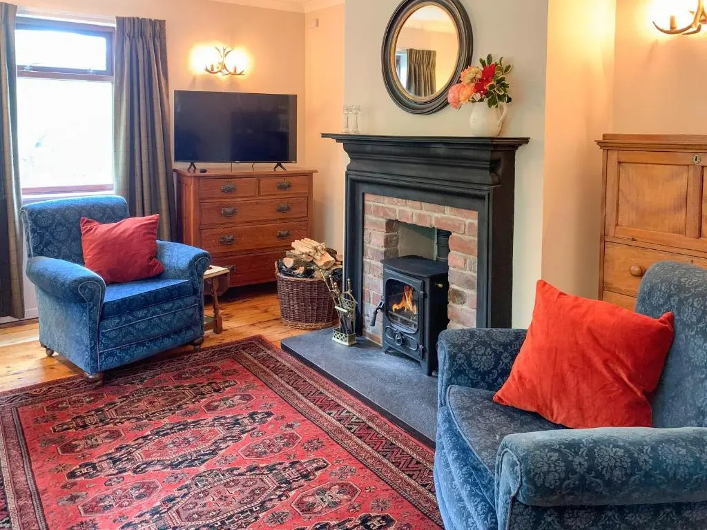a living room with two chairs and a fireplace at Forester's Cottage in Kildary