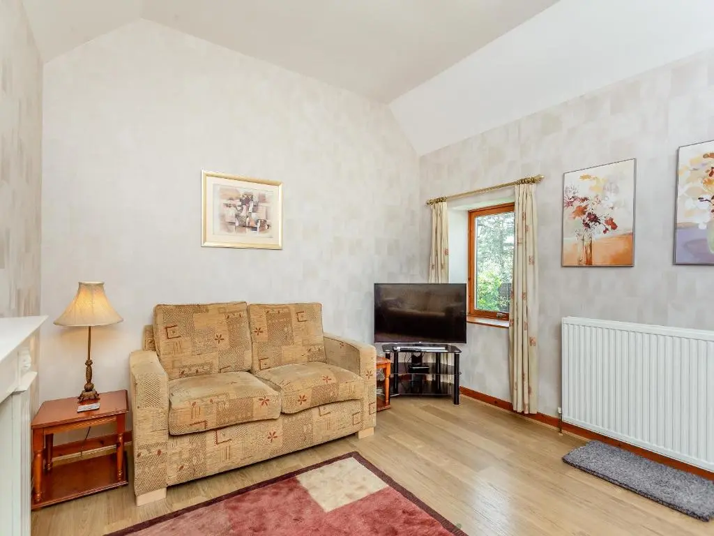 a living room with a couch and a television at The Coyles Cottage - Sbh in Ballater