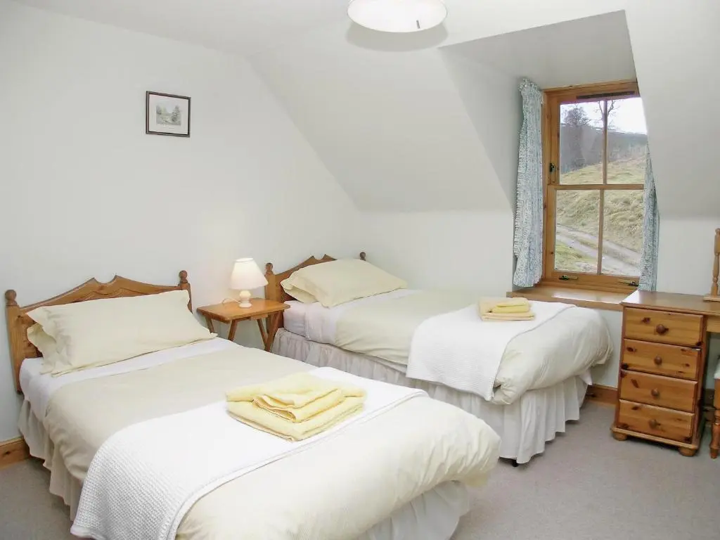 a bedroom with two beds and a window at Mar House in Braemar